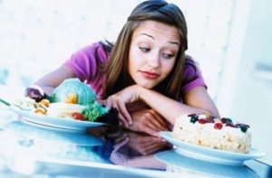 mujer mirando un plato de verduras y una tarta 